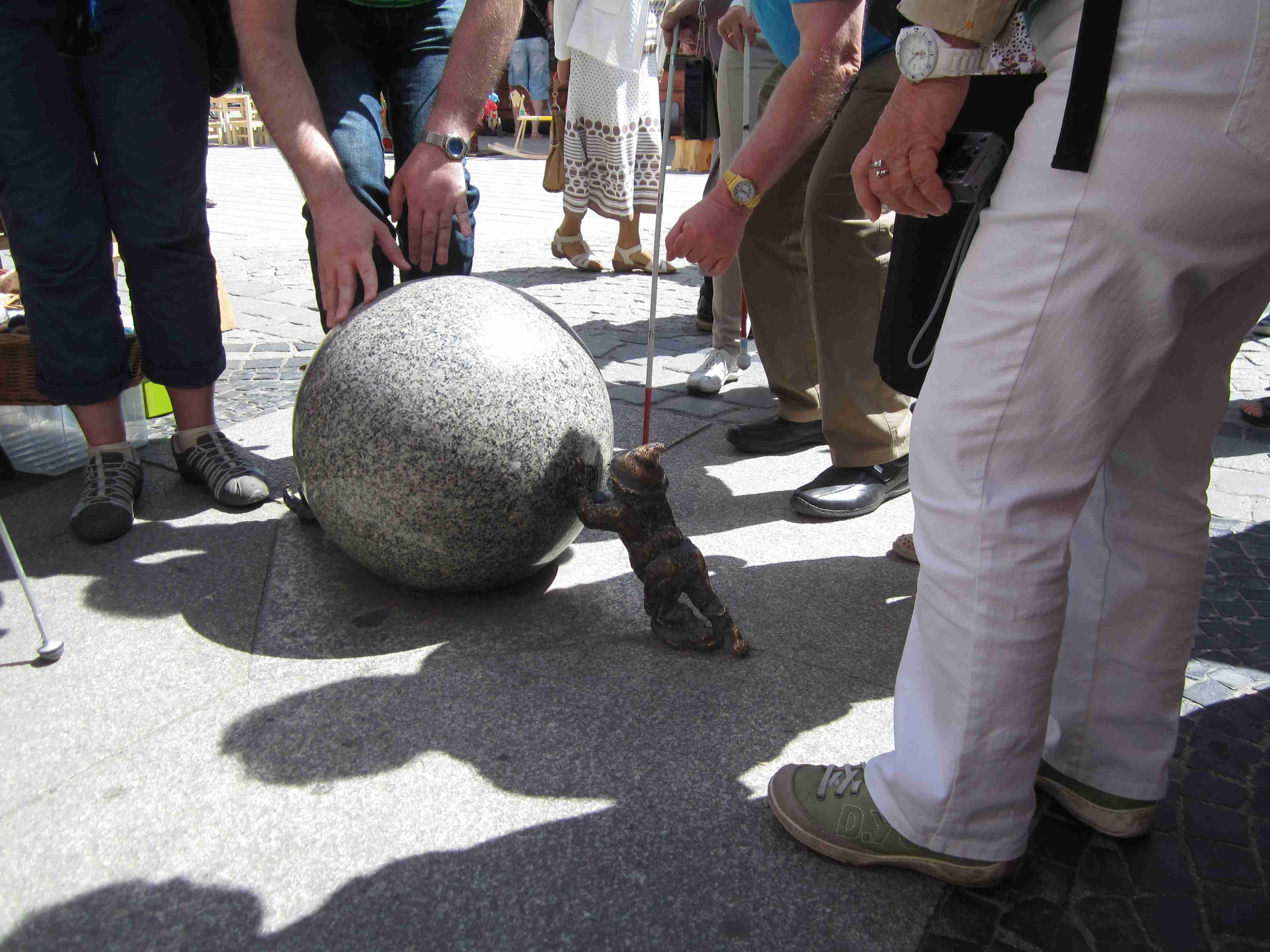 Foto: Der Bronzezwerg Sysiphos schiebt eine Granitkugel über den Breslauer Marktplatz. Foto: C. Zeh